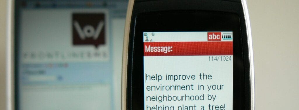 A mobile phone screen showing a text message: help improve the environment in your neighbourhood by planting a tree
